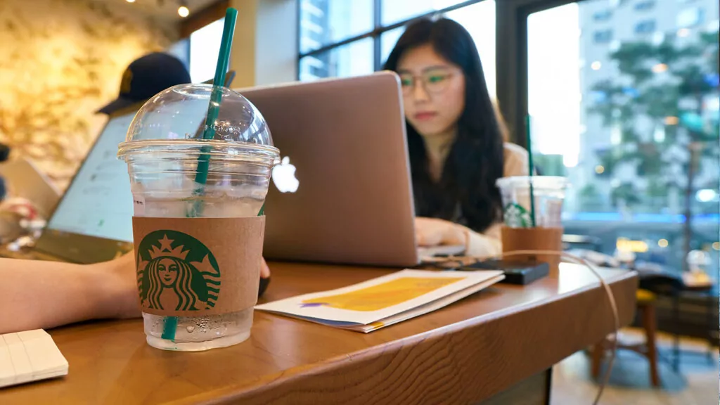 Girls sitting at a Starbucks with a Starbucks cup and a macbook 