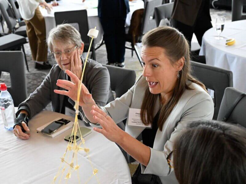 Photo taken during the Together25Ensemble conference featuring a woman constructing a tower out of straws
